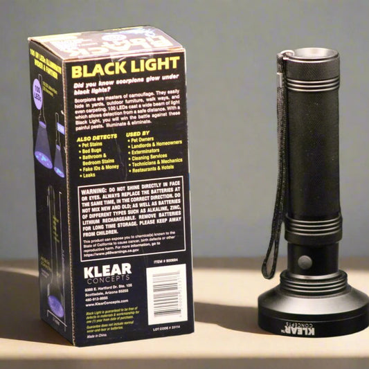 UV blacklight flashlight and back of packaging used for charging glow-in-the-dark disc golf discs, shown on a wooden surface for Lightspeed Disc Golf.